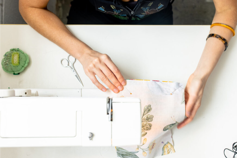 hand pulling fabric through sewing machine