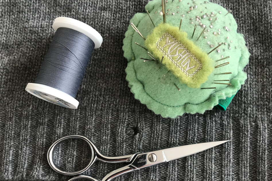 hand pulling fabric through sewing machine